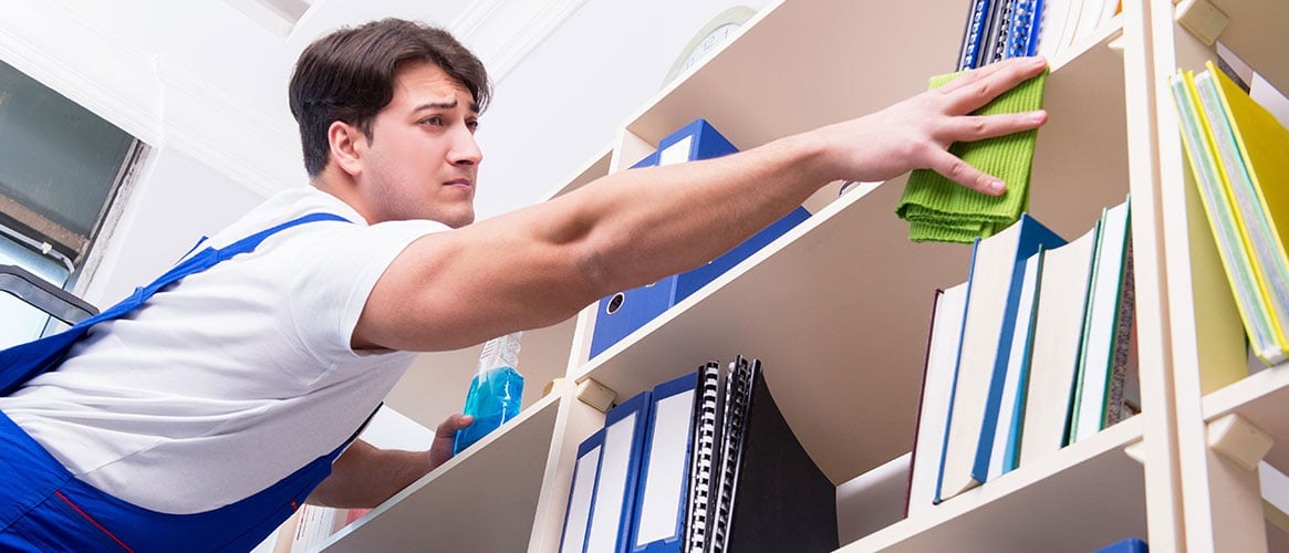 Worker bending and reaching to clean shelves