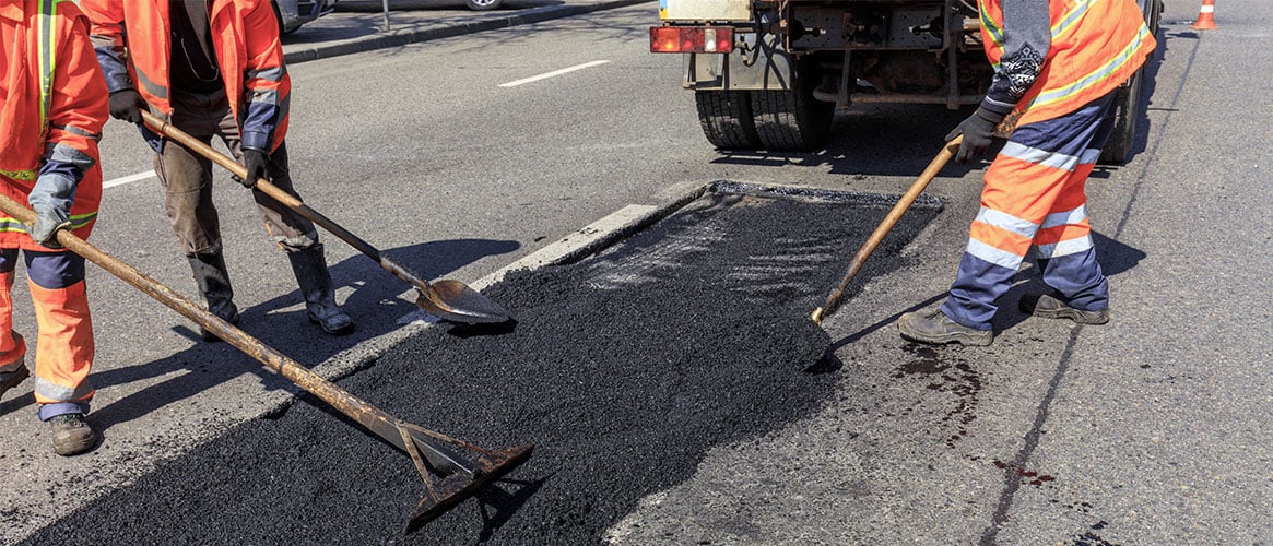 Workers spreading asphalt on a street that's under repair