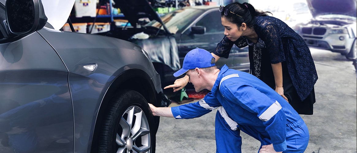 mechanic checking tire wear for customer